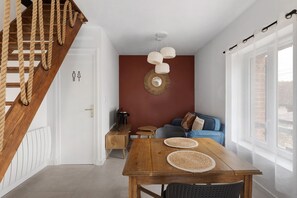 Um interior moderno com escada de madeira, área de jantar com mesa de madeira, sofá e televisão.