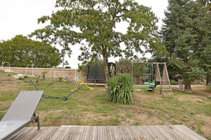 A backyard with a swing set, a slide, a bench, and a wooden deck. - Gite "La Glycine" for 2 with Heated Pool from Mid-May to September (Veuzain-sur-Loire)