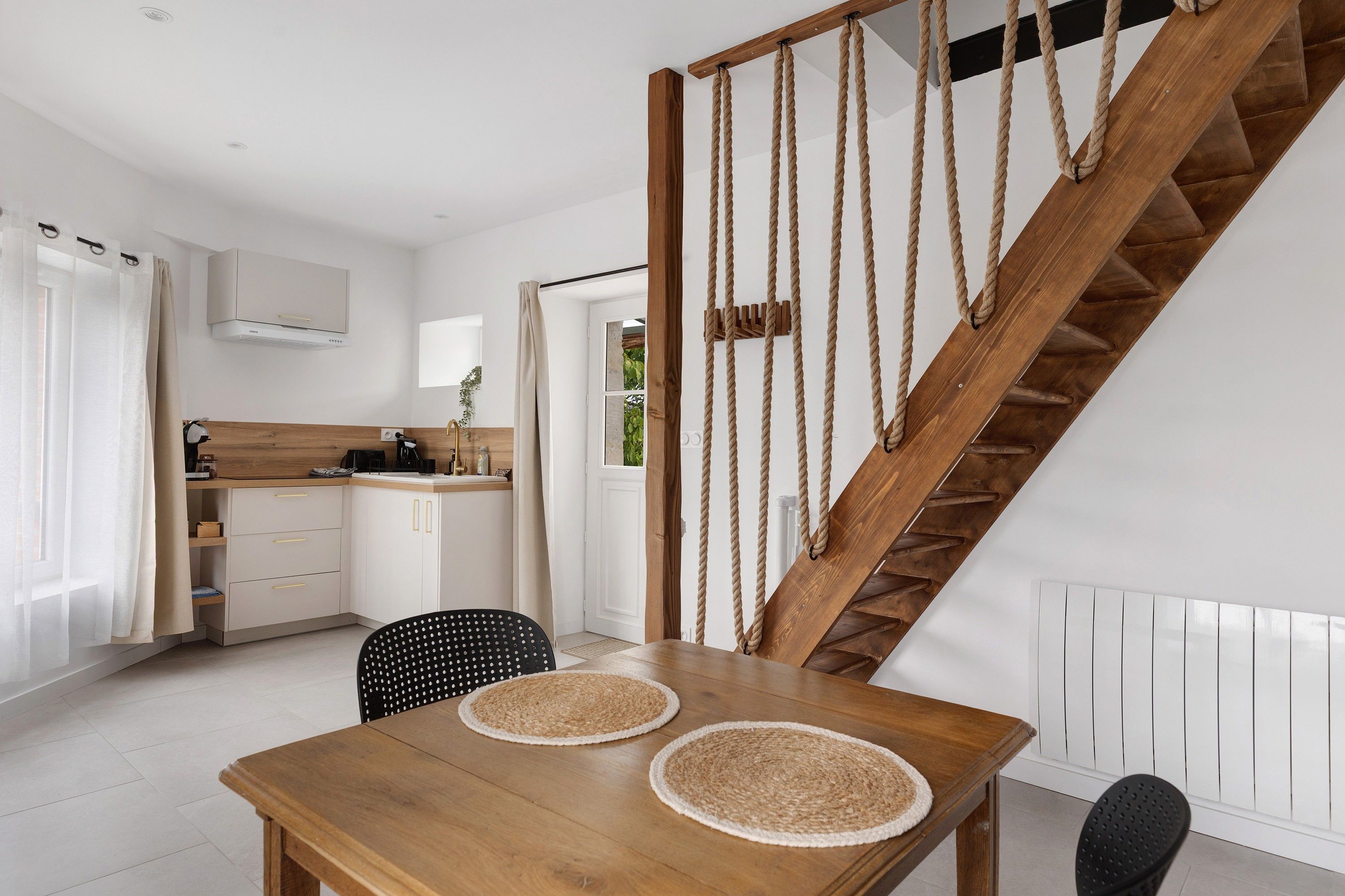 A modern kitchen with white cabinets, a wooden countertop, and a hanging pot rack.