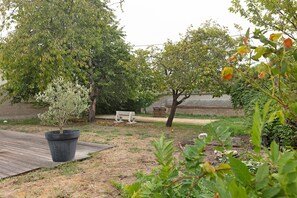 A garden with a wooden deck, a bench, and a variety of trees. - Gite "La Glycine" for 2 with Heated Pool from Mid-May to September (Veuzain-sur-Loire)