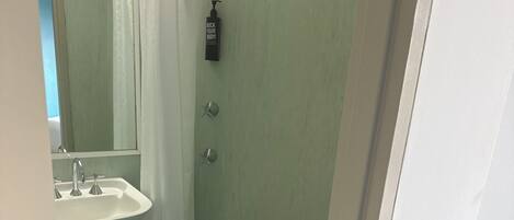 A bathroom with a white sink, a shower with a curtain, and a mirror.