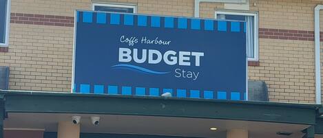 Letrero que dice 'Coffs Harbour BUDGET Stay' en un edificio.