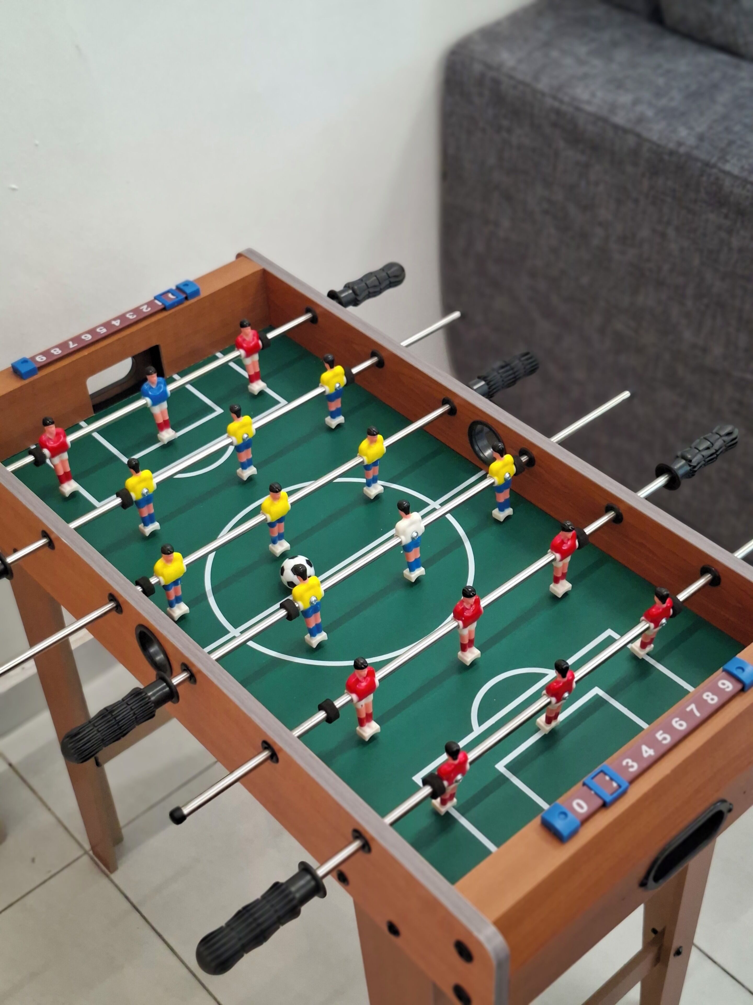 A foosball table with players in red, blue, and yellow uniforms.