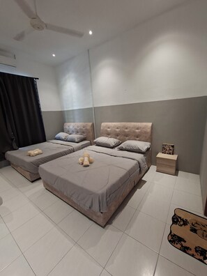 Habitación de hotel con dos camas, ventilador de techo, mesita de noche y una pequeña mesa con un adorno.