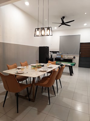 A dining area with a table set for four, chairs, a ceiling fan, a coffee machine, and a pool table.