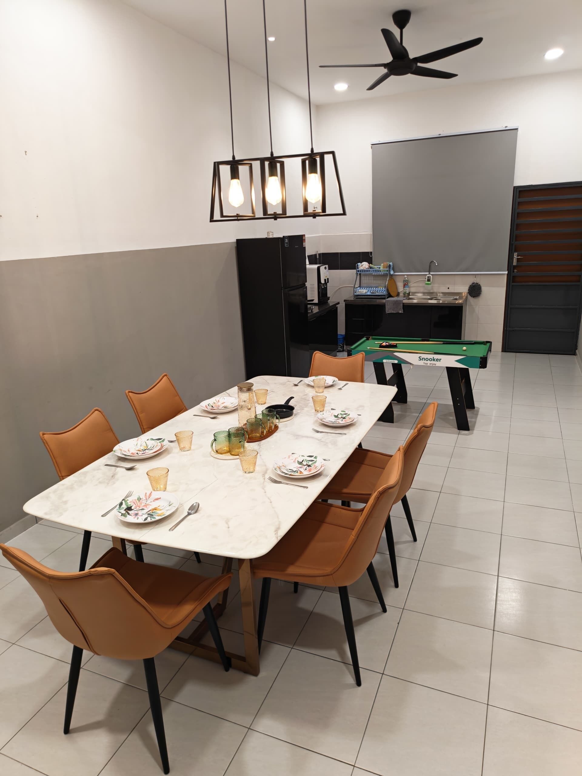 A dining area with a marble table, orange chairs, a pool table, and a ceiling fan.
