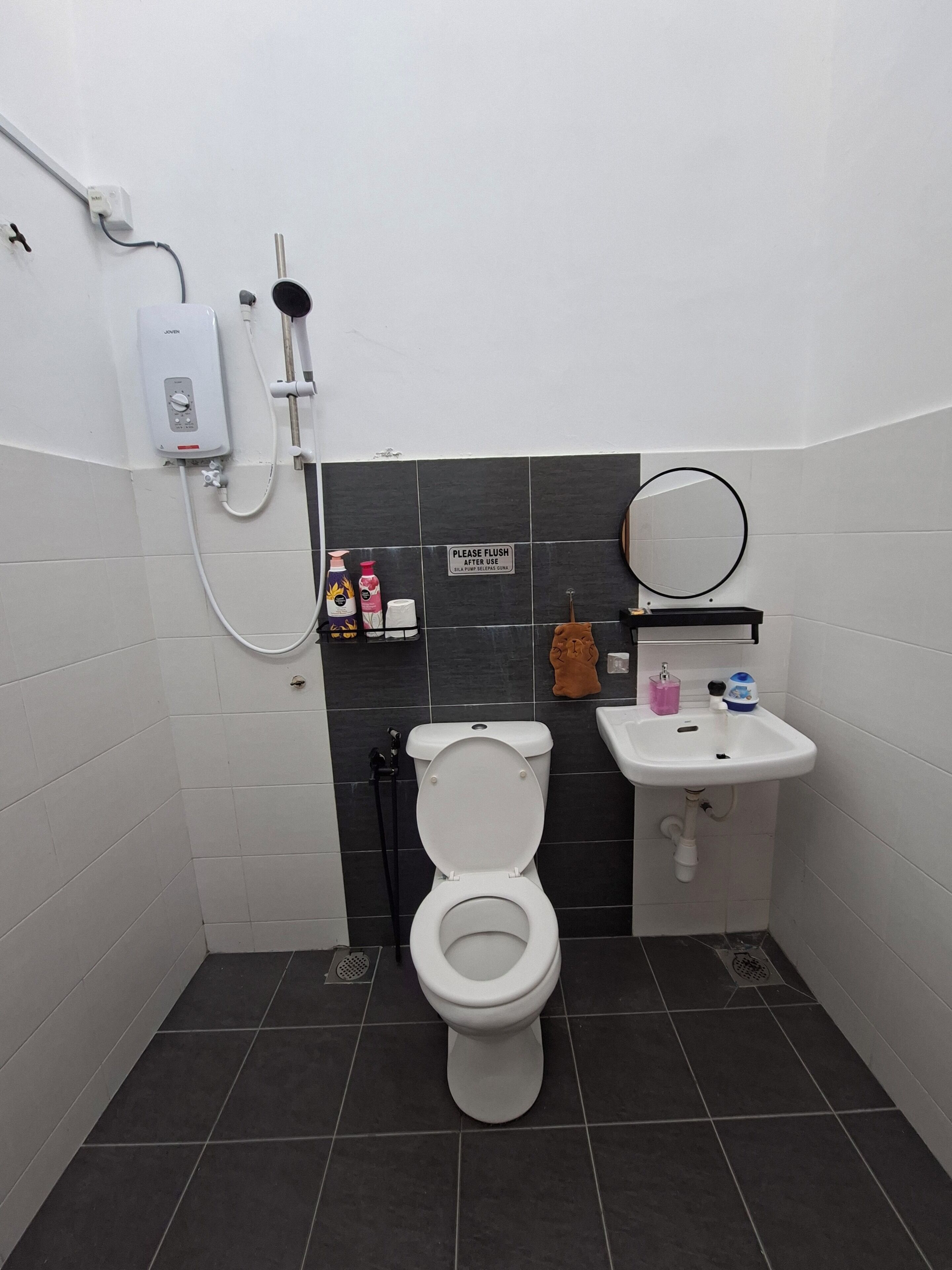 Ein Badezimmer mit Toilette, Waschbecken, Dusche und einem Schild mit der Bitte, nach Gebrauch die Spülung zu benutzen.