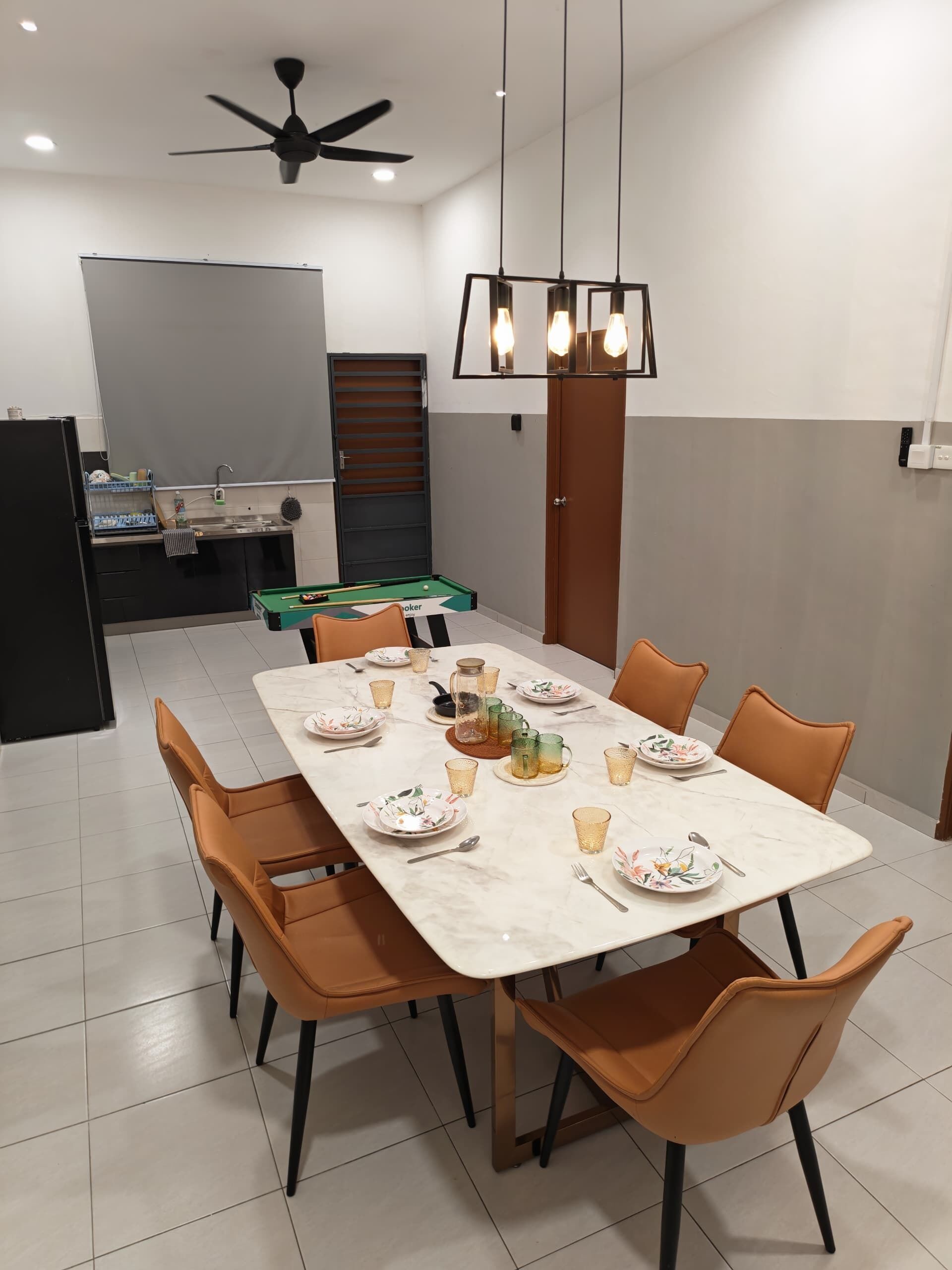 A dining area with a rectangular table set for six, surrounded by orange chairs.