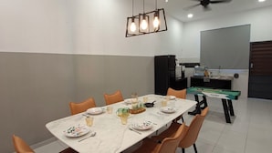 A dining area with a rectangular table, orange chairs, a ceiling fan, and a pool table. - Kuantan putra home (Kuala Lipis)