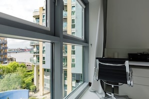 Ein moderner Arbeitsraum mit einem großen Fenster, einem schwarzen Bürostuhl und einem Schreibtisch mit einem Epson-Drucker.