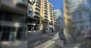 A modern multi-story building with balconies, a clear sky, and a paved street. - Sophisticated 2BD Flat with Riverside Views (Greater London)