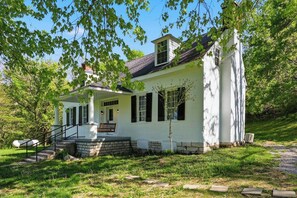 A white house with a porch, steps, and a small tree. - This house is a 3 bedroom(s), 2 bathrooms, located in Frankfort, KY. (Frankfort)