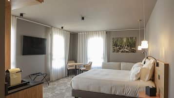 Een hotelkamer met een bed, een bureau, een stoel, een televisie en een schilderij aan de muur.