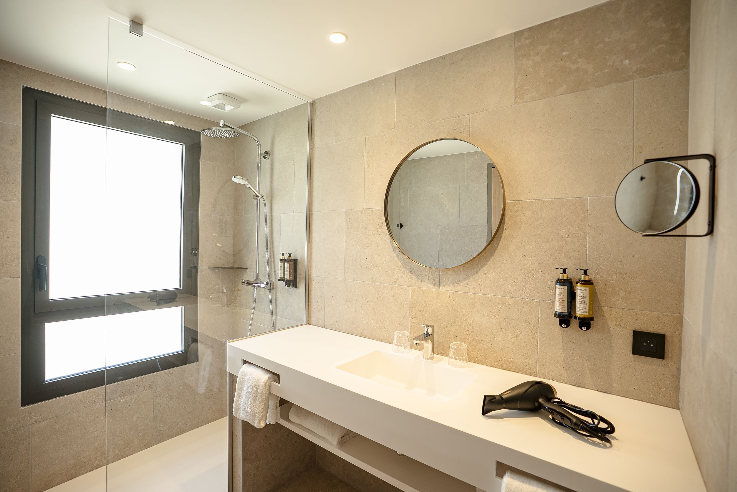 A modern bathroom with a large mirror, a glass shower enclosure, and a white sink with a towel rack.