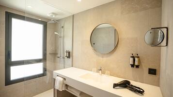 A modern bathroom with a large mirror, a glass shower enclosure, and a white sink with a towel rack.