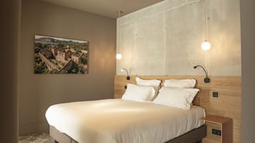 A bedroom with a bed, a nightstand, a wall-mounted lamp, a ceiling light, and a framed picture on the wall.