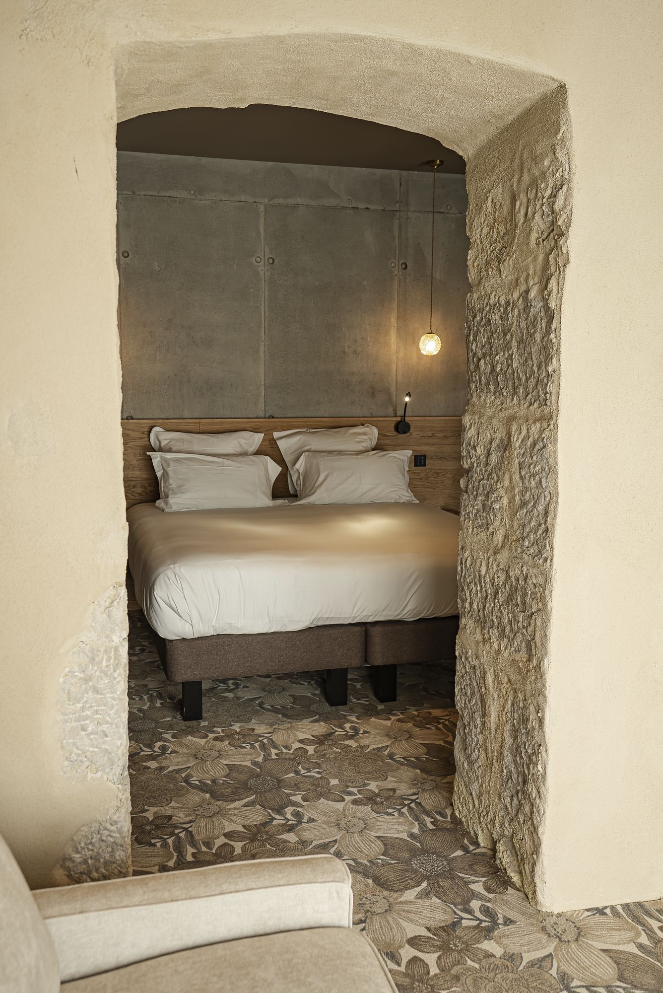A bed with a headboard, pillows, and a nightstand with a lamp.