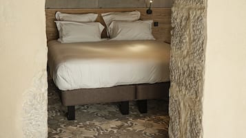A bed with a headboard, pillows, and a nightstand with a lamp.