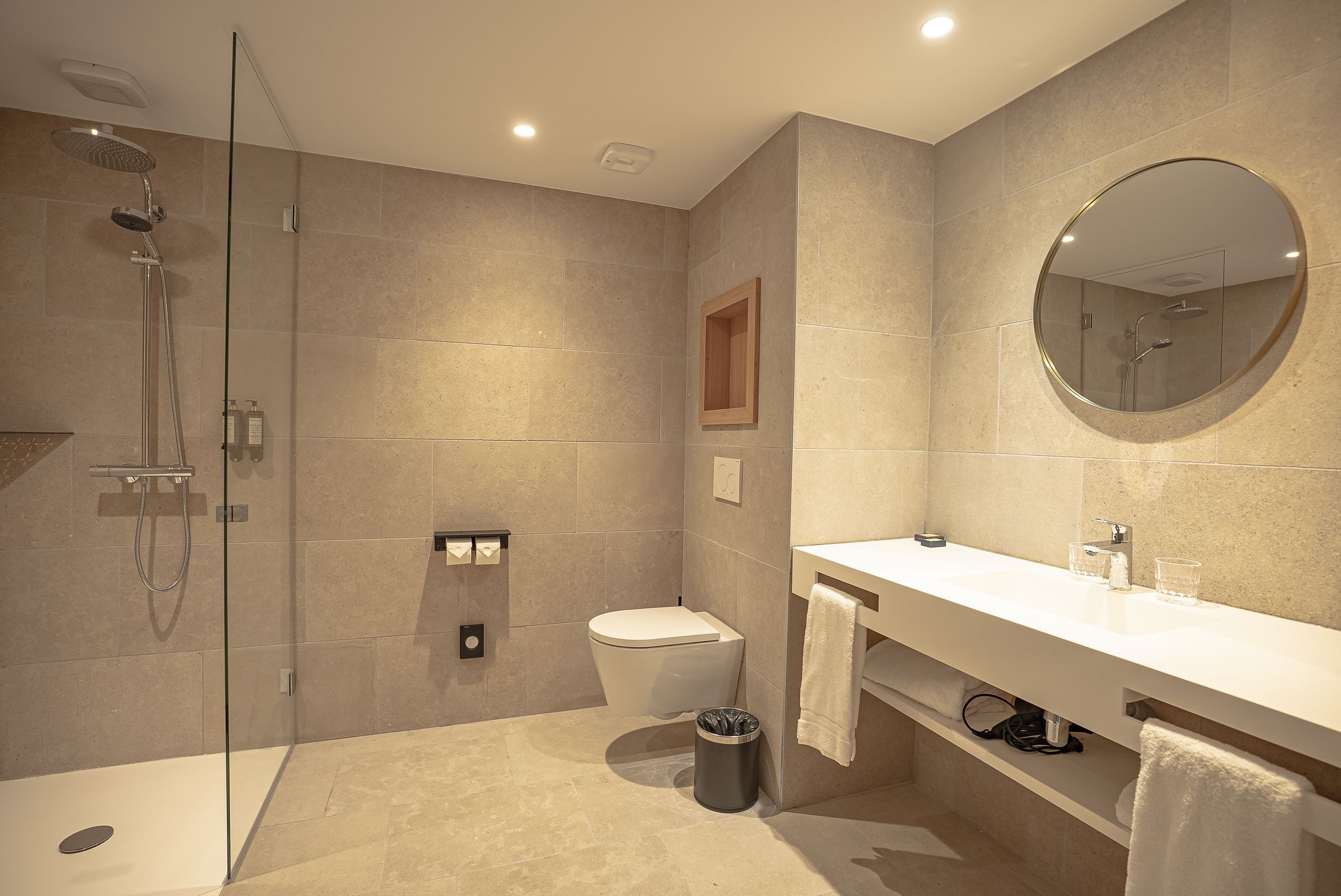 Une salle de bain moderne avec une douche à parois de verre, des toilettes, un lavabo avec un miroir et un porte-serviettes.