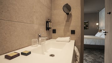 A modern bathroom with a large sink, a mirror, and a towel rack.