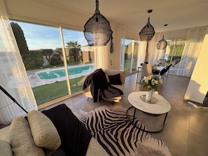A spacious living room with a large window, a pool view, and a dining area. - 130m3 loft with view of Thau Lagoon and sea (Poussan)