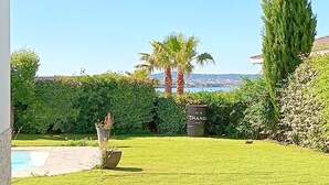 Un espace extérieur abrité offrant une vue sur une piscine et un jardin.