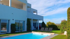 Une maison moderne à deux étages, dotée d’une piscine, de grandes baies vitrées et d’une pelouse bien entretenue.