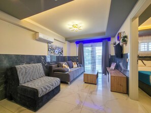 A modern living room with a sofa, a coffee table, and a TV. - 7 - ILEKTRA Suite by SDR (Paralia)