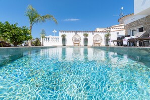 Una piscina cristalina con vistas a un edificio de techos azafrescos y paredes blancas.