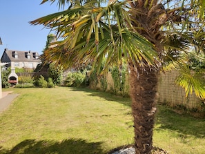 A residential garden with a palm tree, a stone pathway, and a house in the background. - A House Between Land and Sea (Plédran)