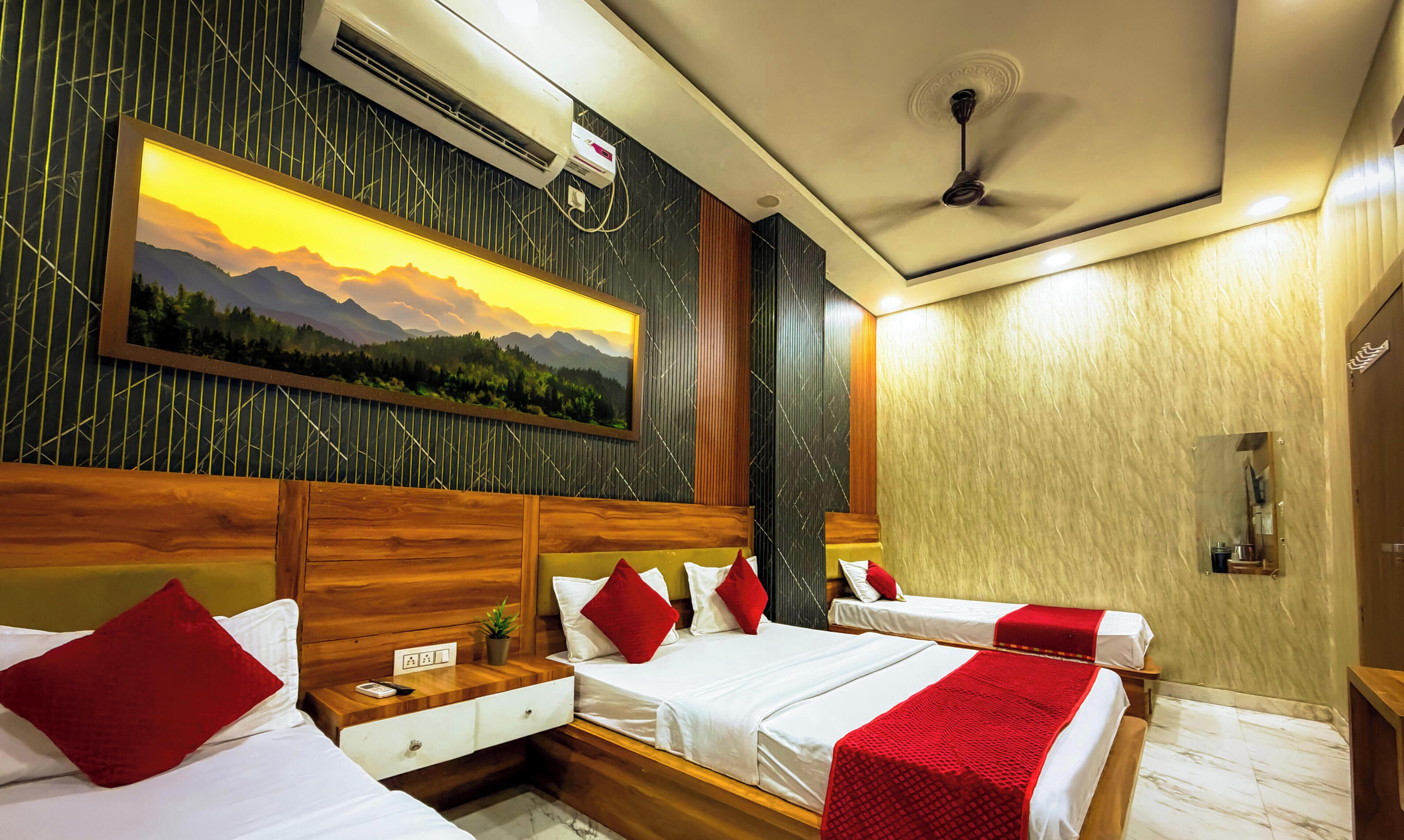 Quarto de hotel com duas camas, um quadro de paisagem montanhosa, aparelho de ar condicionado e ventoinha no teto.