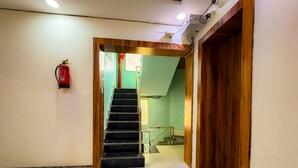 Un pasillo con una escalera que conduce a una habitación con paredes verdes y una puerta de madera.