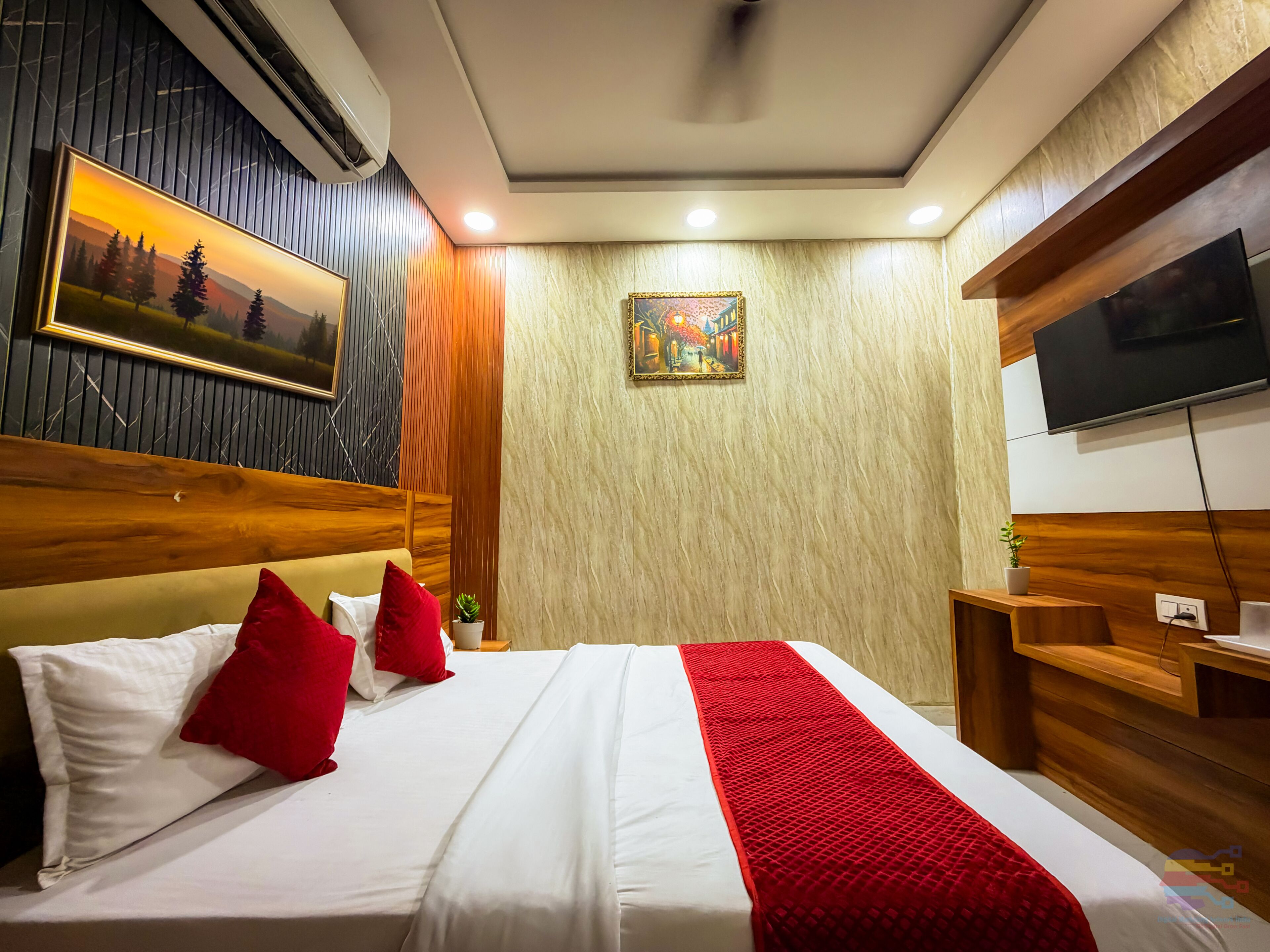Una camera d'albergo con un letto, una televisione, un quadro e una testiera in legno.