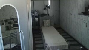 A compact room with a bed, a small kitchenette, and a chair. - Simple Stay Vari s House II (Kropia)