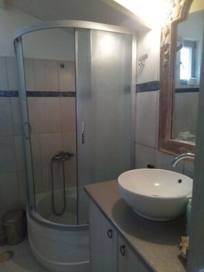 Ein Badezimmer mit einer Duschkabine, einem weißen Waschbecken und einem Spiegel.