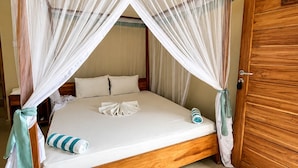 Una cama individual con dosel, una puerta de madera y suelo de baldosas.