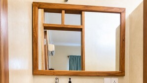 Un baño con lavamanos blanco, tocador de madera y espejo.