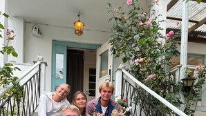 A group of people sitting on a staircase with a dog, surrounded by flowers and a lamp post. - Gåsen Out B&B (Burgsvik)