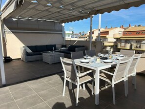 An outdoor patio with a table set for dining, a sofa, and a covered seating area. - Penthouse Sabrina La zenia (Orihuela Costa)