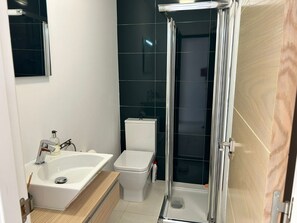 Ein Badezimmer mit einem weißen Waschbecken, einer Toilette und einer Duschkabine.