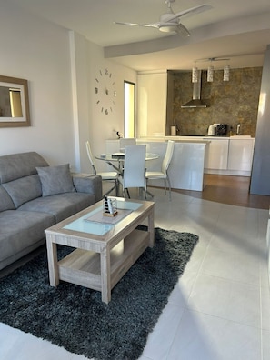 A modern living room with a sofa, coffee table, and dining area. - Penthouse Sabrina La zenia (Orihuela Costa)