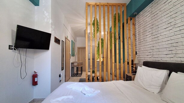 Ein Hotelzimmer mit einem Bett, einem an der Wand montierten Fernseher, einem Feuerlöscher und einer Holzwand.