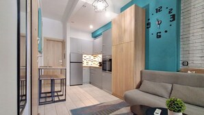Eine moderne Küche mit integriertem Backofen, ein Essbereich mit Tisch und Stühlen sowie ein Wohnzimmer mit Sofa und Couchtisch.