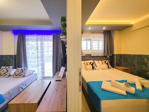 Ein Hotelzimmer mit zwei Betten, einer Holzbank, einem kleinen Tisch und einer Pflanze.