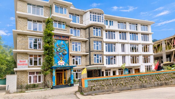 Un hotel de varios pisos con una entrada destacada, balcones y fachada de piedra.