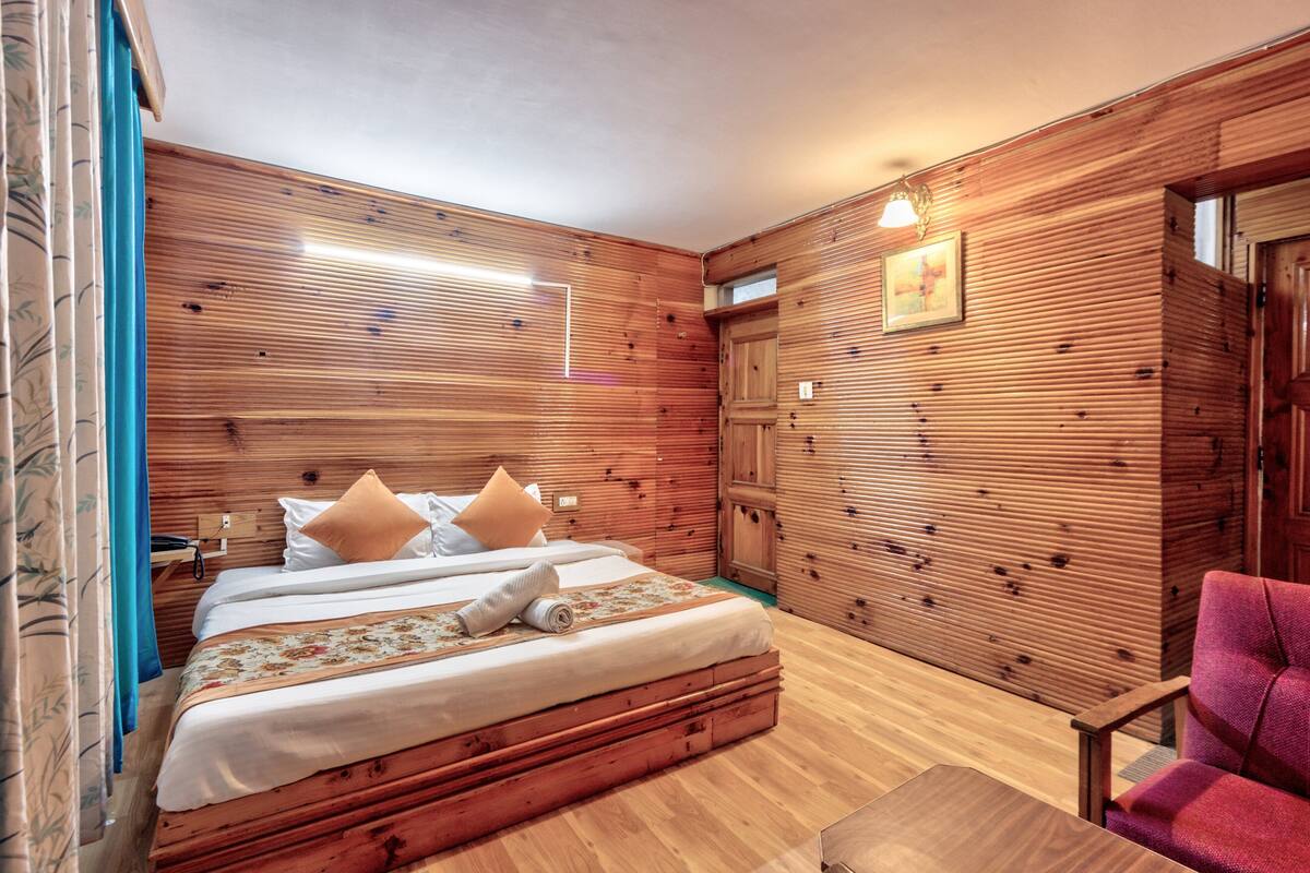 Una habitación con paneles de madera, una cama, una silla y una pequeña mesa.