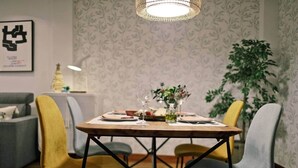 A dining area with a table set for two, chairs, a hanging light fixture, and a plant in the background. - COSY APARTMENT closed to RIVERSIDE & Parking (Bilbao)