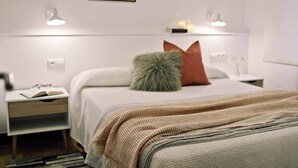 A hotel room with a bed, bedside tables, a nightstand, a lamp, and a wall-mounted picture. - COSY APARTMENT closed to RIVERSIDE & Parking (Bilbao)