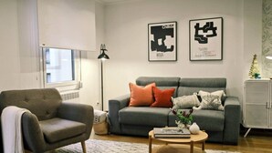 A living room with a grey sofa, a grey armchair, a coffee table, and two framed artworks on the wall. - COSY APARTMENT closed to RIVERSIDE & Parking (Bilbao)