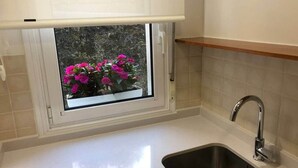 A kitchen with a window, a sink, and a wooden shelf. - COSY APARTMENT closed to RIVERSIDE & Parking (Bilbao)
